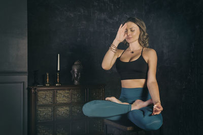 A charming girl in a sports uniform does yoga in an old room with a fireplace and candles