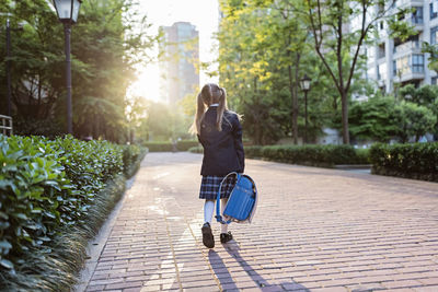 Rear view of girl walking on footpath