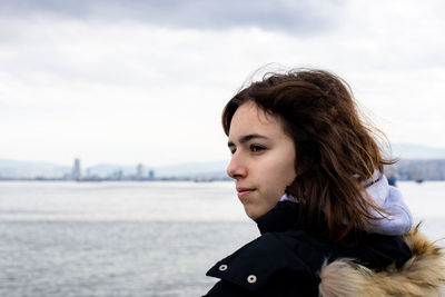 Pensive young girl looking to the sea from boat. teenager girl at ferryboat. city view at background