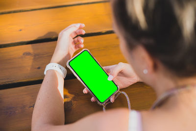 Midsection of woman holding mobile phone while sitting on table