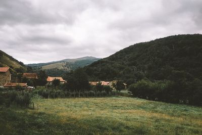 Houses on field against cloudy sky