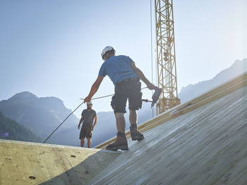 Carpenter holding drill working on roof at construction site