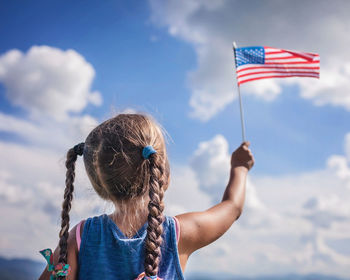 Patriot and national flag day celebration. little patriot sitting on the meadow and holding usa flag