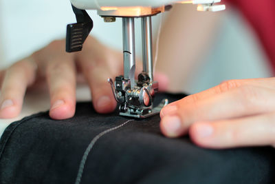Close-up of hand using sewing machine