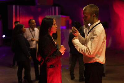 Businessman discussing with female colleague during conference event in illuminated workshop