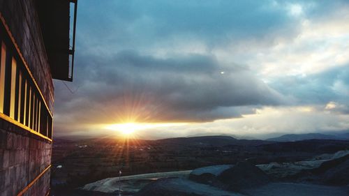 Sun shining through clouds over mountains