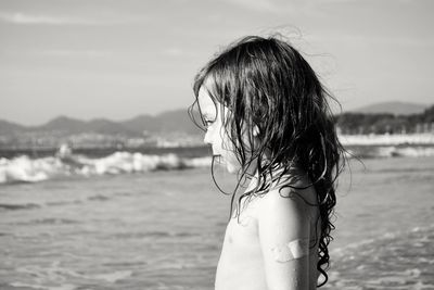 Side view of girl at beach against sky