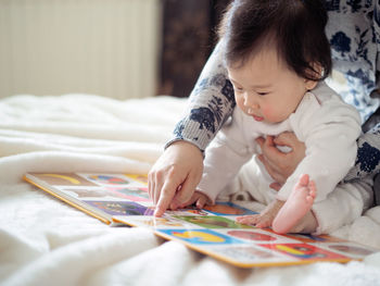 Close-up of mother teaching daughter to read