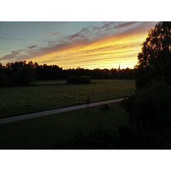 Scenic view of grassy field against sky at sunset