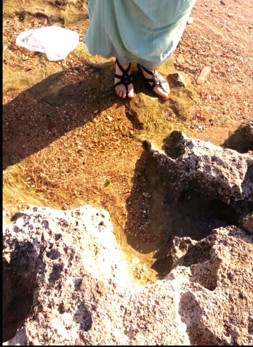 LOW SECTION OF MAN WITH SHADOW ON SAND