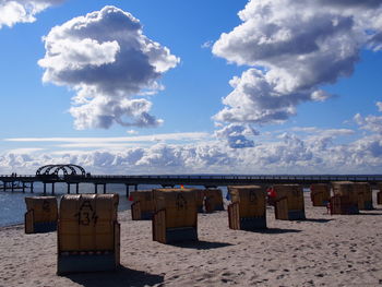 Deck chairs on beach against blue sky