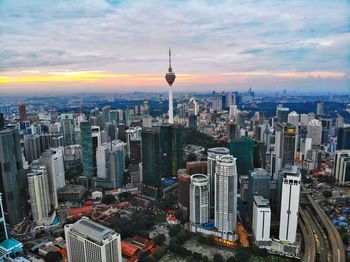 Aerial view of buildings in city against cloudy sky