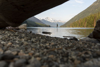 Ground level of unrecognizable man on paddle board on lake at sunrise.