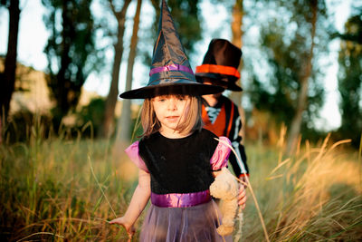 Cute siblings in costume against trees during halloween