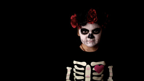 Portrait of girl wearing mask against black background