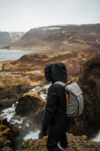 Full length of hiker standing on cliff against sky