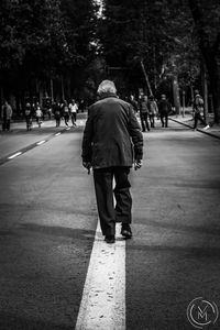 Rear view of man walking on road
