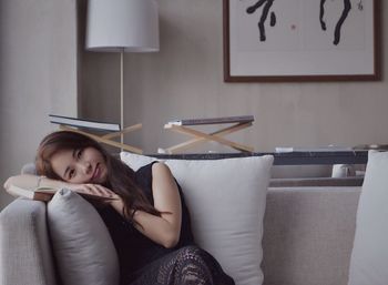 YOUNG WOMAN SITTING ON SOFA