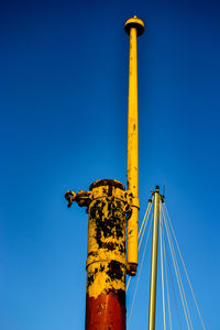 Low angle view of yellow crane against clear blue sky