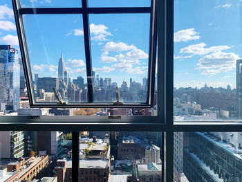 View out of the windows framing nyc cityscape with empire state building against blue sky