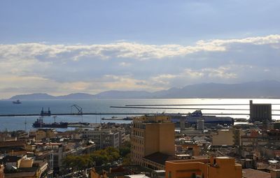 Cityscape by sea against sky