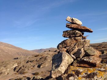 Bird perching on rock against sky