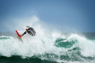 Person surfing on sea against clear sky