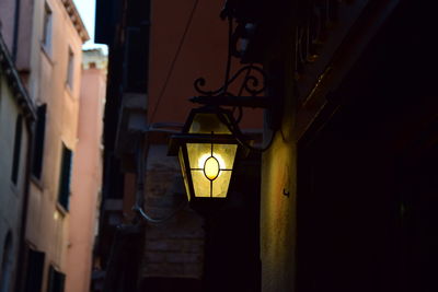 Low angle view of illuminated lamp hanging on street light at night
