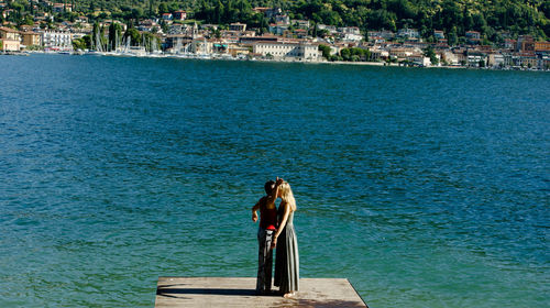 Friends standing on pier against lake