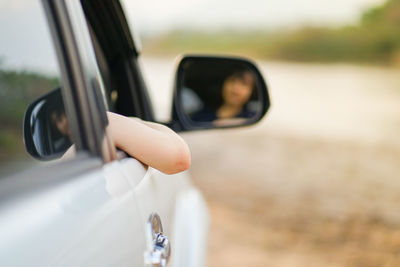 Woman in car reflecting on side-view mirror