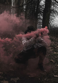 Woman with pink petals on trees in forest