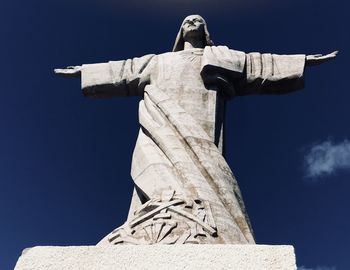 Low angle view of jesus christ statue against blue sky