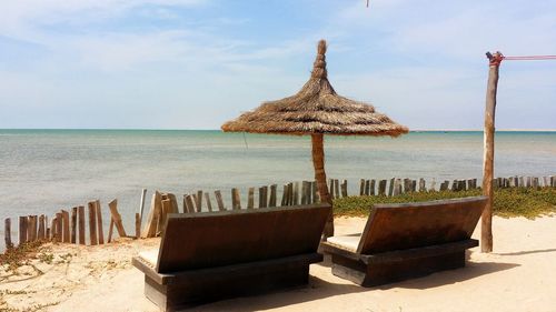 Lounge chairs on beach against sky