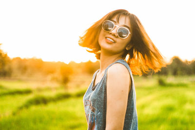 Side view of smiling young woman standing on field