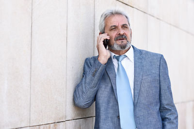 Mature man using mobile phone while standing outdoors