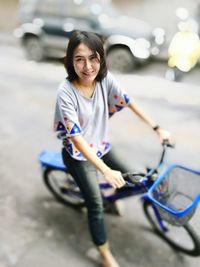 Tilt-shift image of young woman riding bicycle on streets