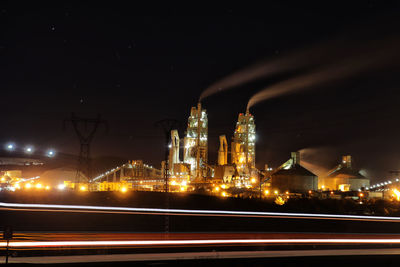 Illuminated light trails on road against sky at night