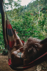 Woman sitting on hammock against plants