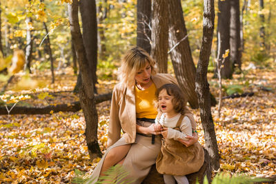 Girl and woman standing by tree during autumn