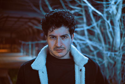 Portrait of young man standing against bare tree