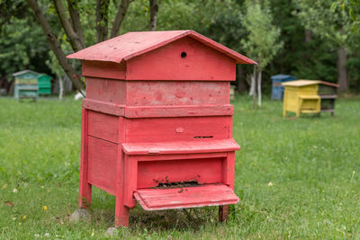 Red beehive box on grassy field