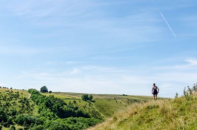 Woman walking on field against sky