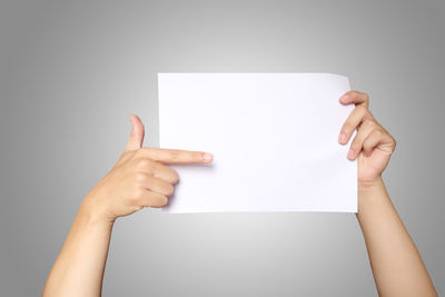 Low section of person holding paper against white background