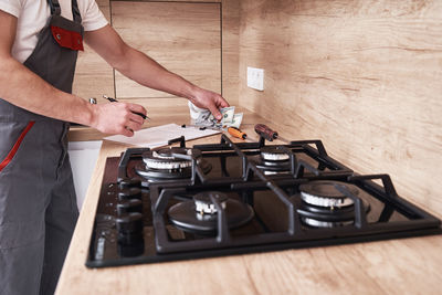 Plumber in uniform signs a contract for services in the kitchen