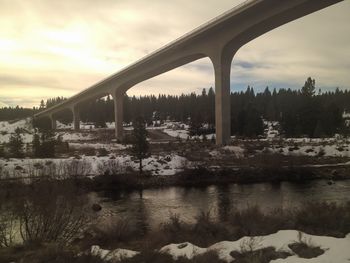 Bridge over river against sky during winter