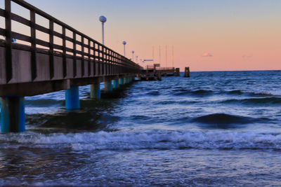 Pier over sea against sky during sunset