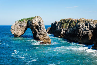 Rock formation in sea against sky