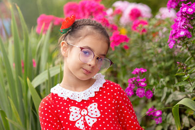 A portrait of beautiful little girl in glasses in blossom garden