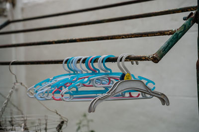 Low angle view of multi colored clothespins hanging on rope against wall