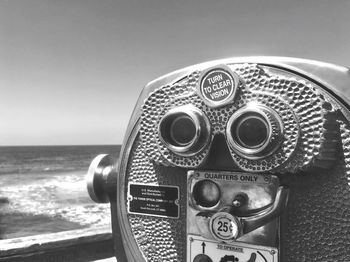 Close-up of coin-operated binoculars by sea against clear sky